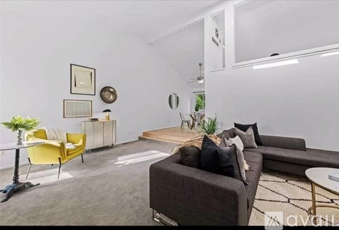 A living room with a yellow chair and a brown couch.