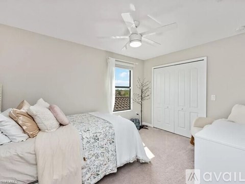 A bedroom with a large bed and a window overlooking a fence.