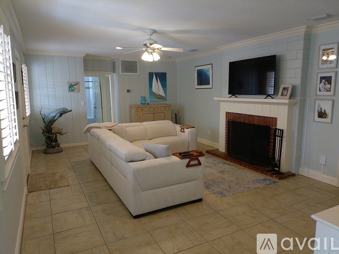 A living room with a white couch and a fireplace.