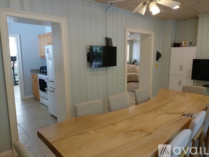 A kitchen with a wooden table and a television mounted on the wall.