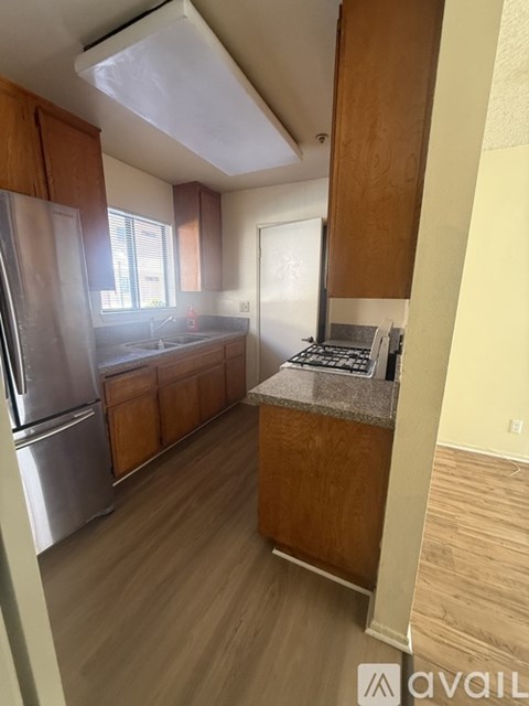 A kitchen with wooden cabinets and a stainless steel refrigerator.
