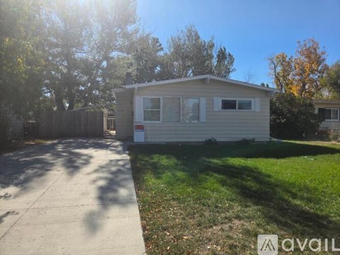A mobile home sits in a driveway with a sidewalk and trees in the background.