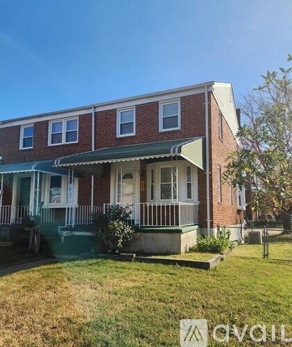 A red brick house with a green awning and white trim.
