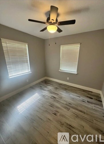 A room with a ceiling fan and wooden flooring.