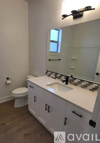 A bathroom with a toilet, sink, and mirror.