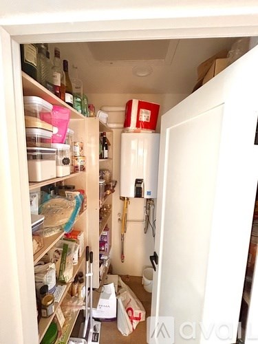 A small, cluttered kitchen pantry with a white door.
