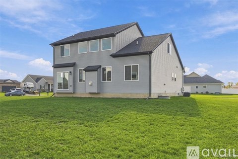 A large house with a grey exterior is surrounded by a green lawn.