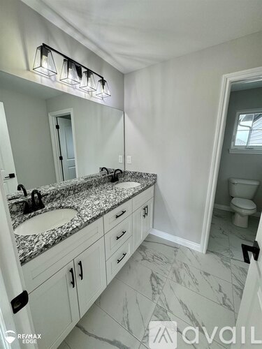 A bathroom with a marble countertop and a large mirror above the sink.