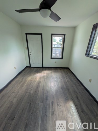 A room with a ceiling fan and wooden flooring.