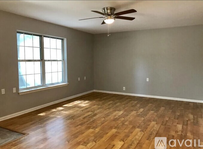 A room with wooden flooring and a ceiling fan.