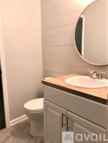 A bathroom with a toilet, sink and mirror.