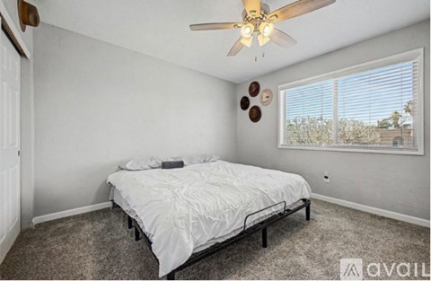A bedroom with a bed, a ceiling fan, and a window with blinds.