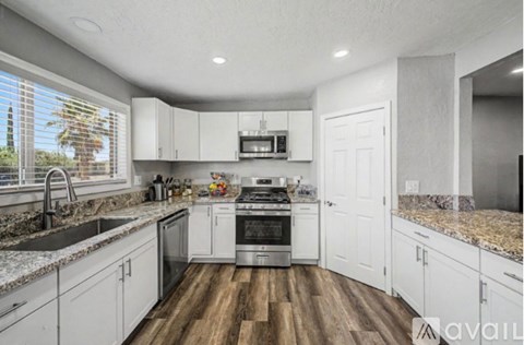A kitchen with white cabinets and a wooden floor.