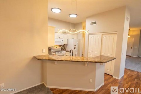 A kitchen with a granite countertop and a white refrigerator.
