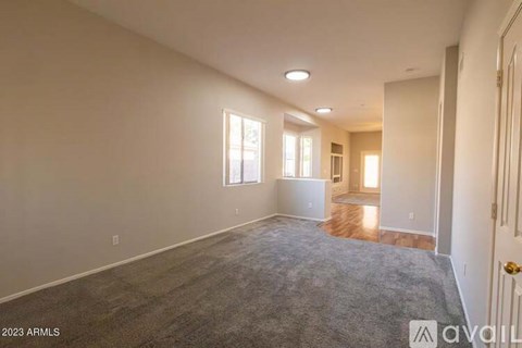A spacious room with a carpeted floor and a door on the right side.