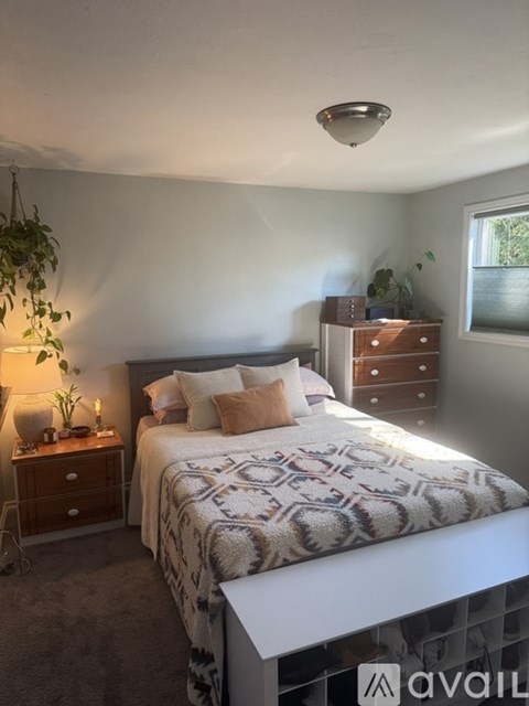 A bedroom with a bed, nightstand, and a window.