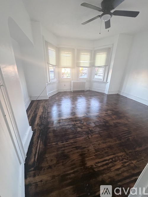 A room with a ceiling fan and wood flooring.