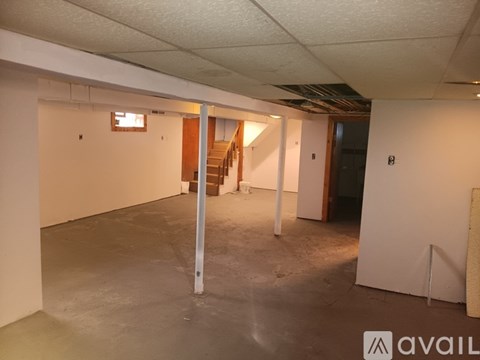 A spacious room with a staircase in the background.
