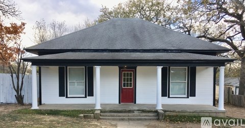 A white house with a red door and a black roof.