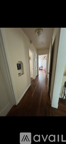 A long hallway with a sign on the wall and a door at the end.