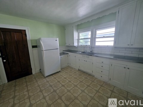 A kitchen with a white fridge and tiled floor.