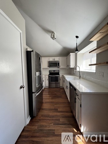 A kitchen with white cabinets and a wooden floor.