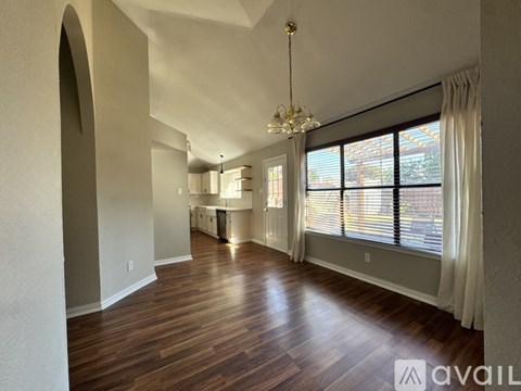 A spacious room with wooden floors and a chandelier hanging from the ceiling.