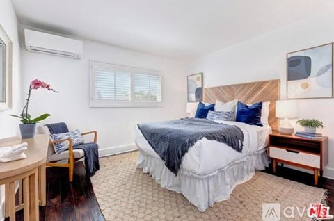 A bedroom with a large bed and a chair.