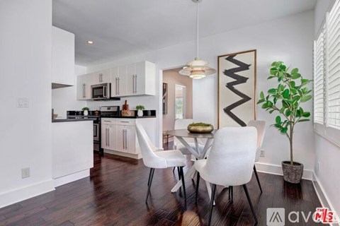 A modern kitchen with white cabinets and a dining table with white chairs.