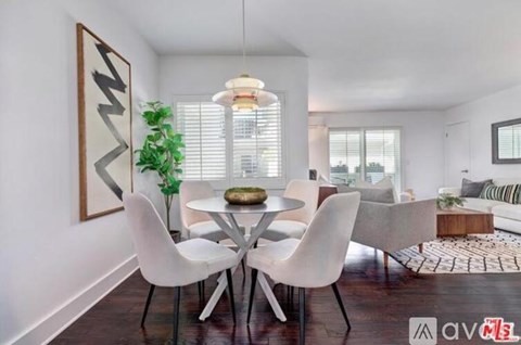 A modern dining room with a white table and chairs.