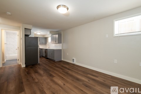 A kitchen area with a refrigerator, cabinets, and a window.