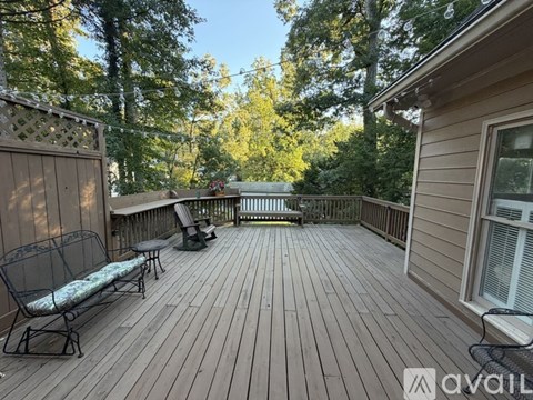 A wooden deck with a bench and a table surrounded by trees.