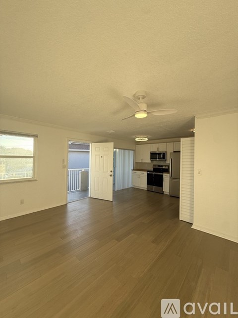A spacious living room with a ceiling fan and hardwood flooring.