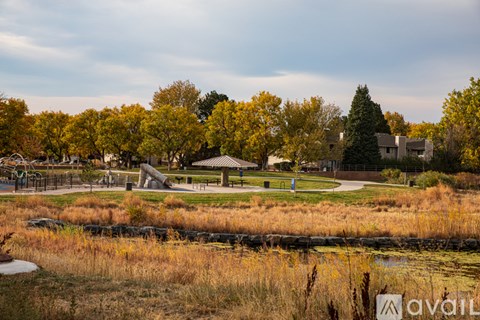 A park with a gazebo surrounded by trees and a pond.