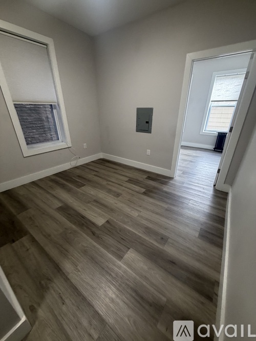 A room with wooden flooring and a window with blinds.