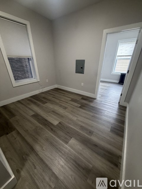 A room with wooden flooring and a window with blinds.