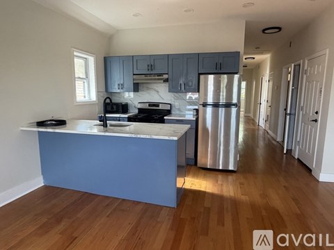 A kitchen with a blue island and stainless steel appliances.