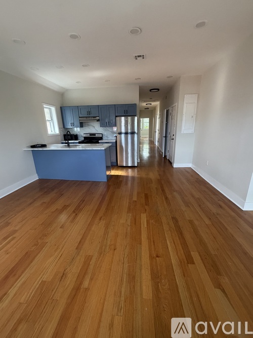 A kitchen with wooden floors and a blue island.