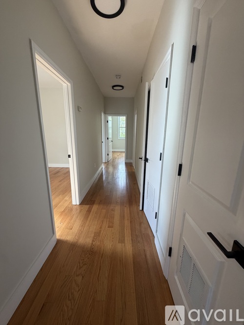 A long hallway with white doors and wooden floors.