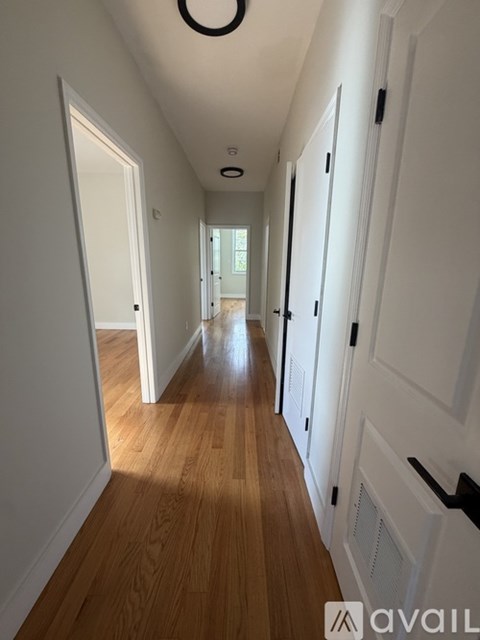 A long hallway with white doors and wooden floors.