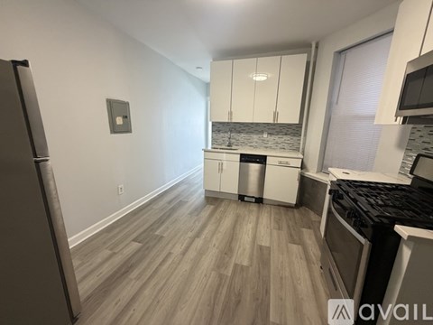 A kitchen with a refrigerator on the left and a countertop with a microwave on the right.