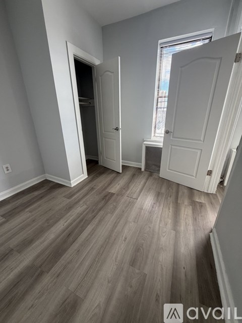 A room with wooden flooring and two doors, one of which is open.