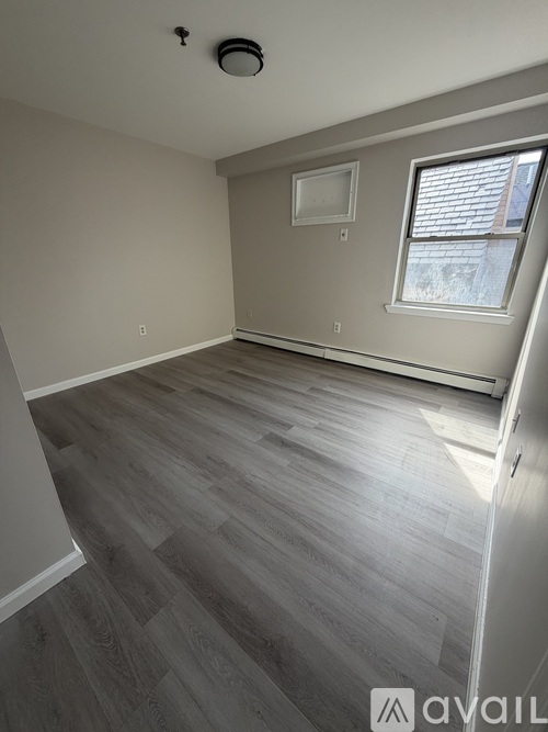 A room with wooden flooring and a window.