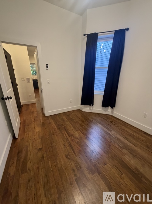 A room with wooden flooring and a window with blue curtains.