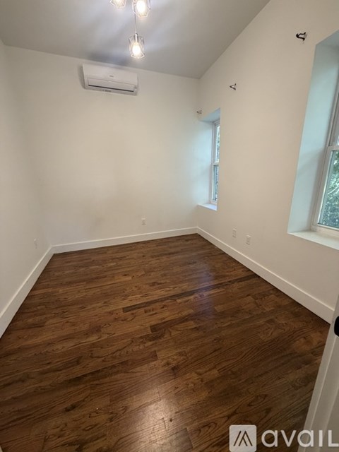 A room with wooden flooring and an air conditioner on the wall.