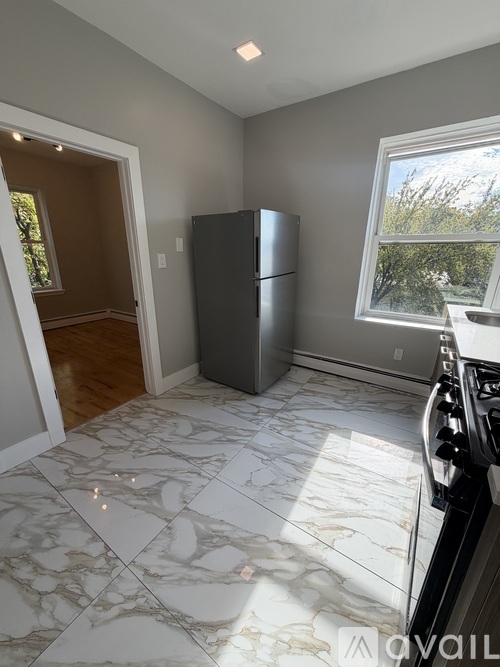 A kitchen with a marble floor and a window.