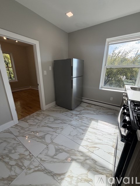 A kitchen with a marble floor and a window.