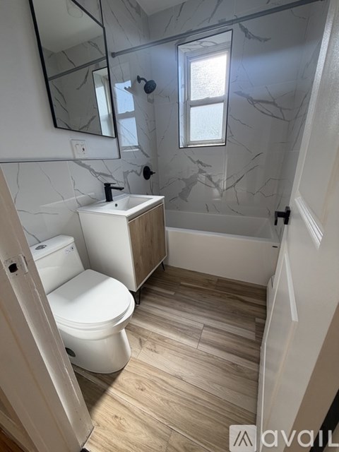 A bathroom with a toilet, sink, and a mirror.