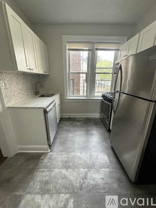 A kitchen with a refrigerator, sink, and cabinets.