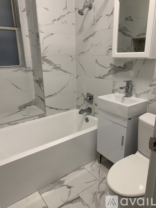 A bathroom with marble tiles and a white toilet.